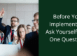 before you implement AI ask yourself one question. Person in a business setting raising hand.