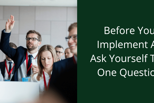 before you implement AI ask yourself one question. Person in a business setting raising hand.